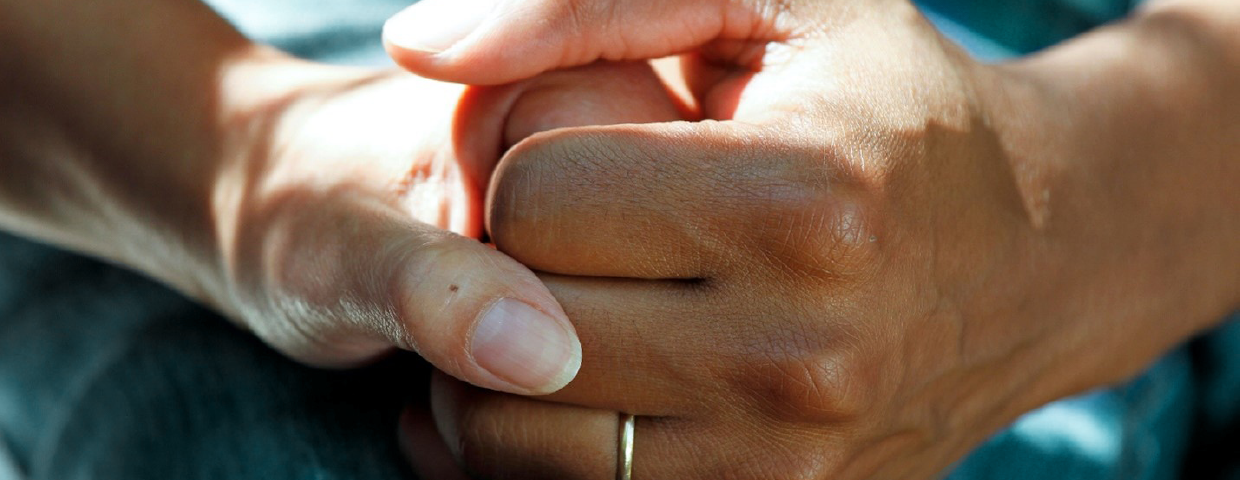 A person holding their friend's hand in support.